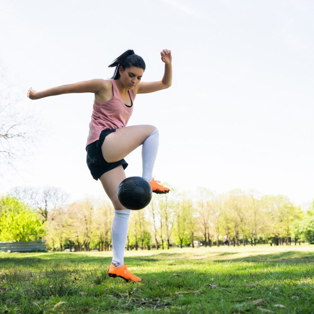 Person playing soccer in a park with trees in the background